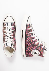 Sneaker alte con un motivo floreale nei toni del rosa e del nero, punta in gomma bianca e dettagli a strisce nere. Materiale in cotone.