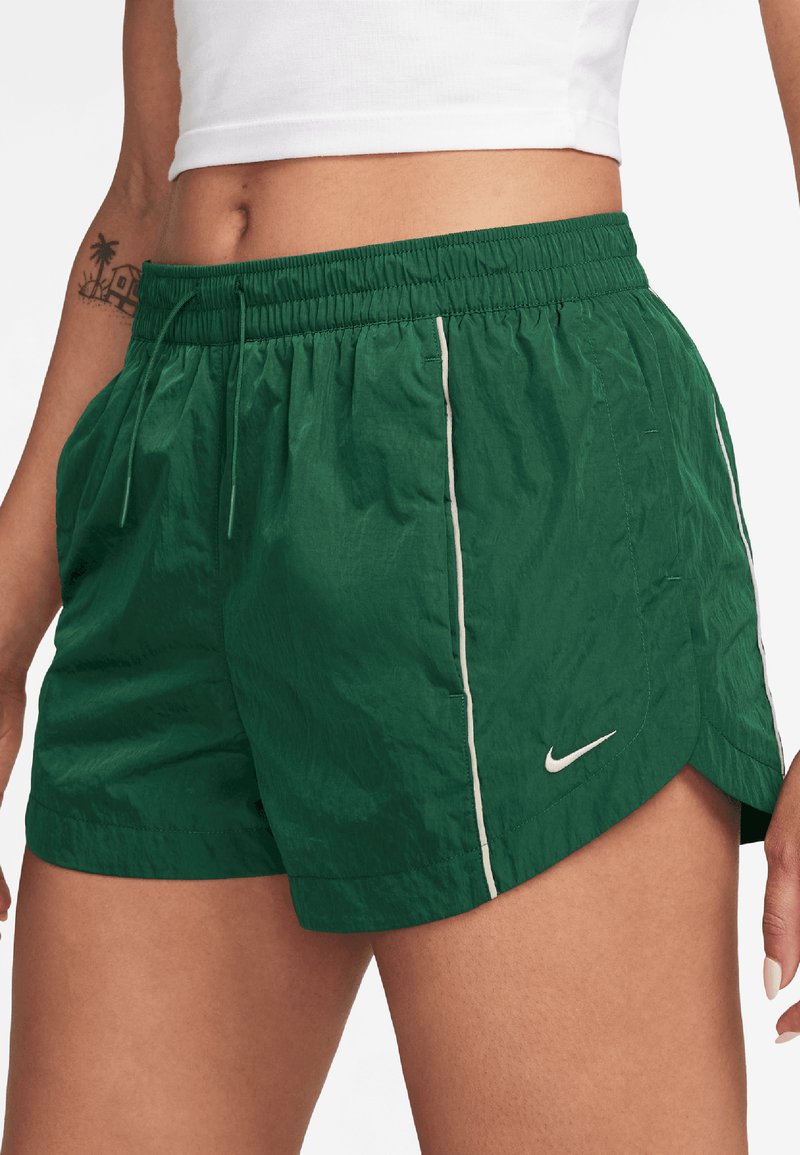 Shorts légers verts avec des rayures blanches sur les côtés, taille élastique et ourlet arrondi. Présente un petit logo Nike sur le devant.