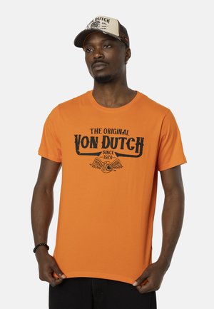 T-shirt en coton orange avec un logo noir imprimé comprenant des ailes et le texte "The Original Von Dutch since 1929". Col rond et manches courtes.