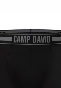 Boxer briefs neri in cotone, con un morbido elastico in vita recante la scritta "CAMP DAVID" in grassetto grigio e dettagli a contrasto.