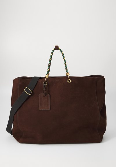 Borsa a tote in suede marrone con manici intrecciati verde e giallo, dettagli in hardware dorato e un'etichetta in pelle attaccata. Include una tracolla rimovibile.