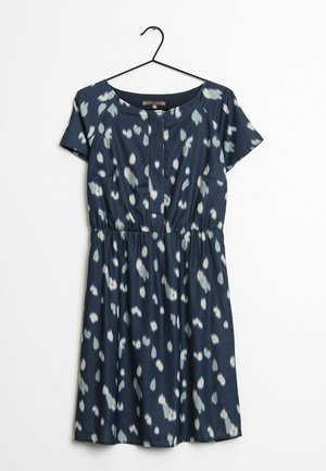 Robe bleu marine à manches courtes avec des taches irrégulières blanches et gris clair, taille cintrée, encolure ronde, suspendue sur un cintre noir sur fond blanc.