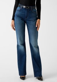 Jeans svasati in denim blu con vita alta, caratterizzati da una cintura nera con fibbia argentata. Tessuto liscio e leggero scolorimento sulle cosce.
