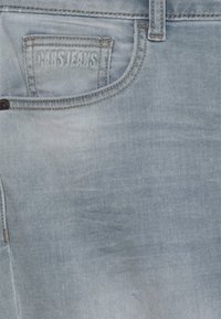 Jeans de mezclilla azul claro con un acabado texturizado, ribetes cosidos y un bolsillo trasero estampado con "PARS JEANS."