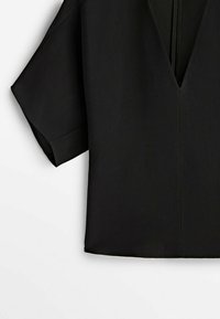 Schwarzes kurzärmeliges Oberteil mit V-Ausschnitt, das eine glatte, matte Textur und einen minimalistischen Stil aufweist, ohne sichtbare Muster oder Verzierungen.