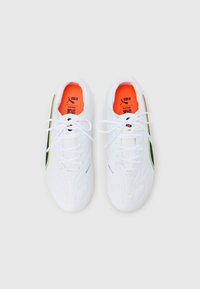 Białe buty sportowe o gładkiej fakturze, z czarnymi i neonowozielonymi akcentami oraz jasnopomarańczową wkładką. Sznurowadła są białe.