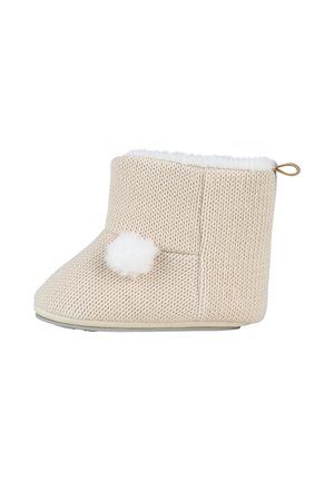 Strikket beige baby-futteral med hvid pelsforing, en fluffet kvast på siden og en lille løkke bagpå for nem at tage den på.