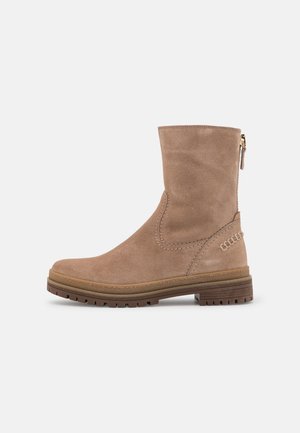 Bota de ante beige de altura media con cremallera lateral, detalles cosidos y suela de goma resistente, mostrada en perfil derecho sobre fondo blanco.