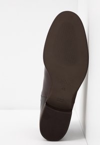 Semelle d'une chaussure en cuir marron affichant la marque "Gabor", la taille 4½, et le texte "Fabriqué en Slovaquie".