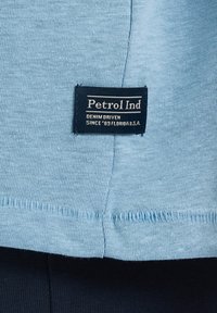 Lichtblauwe katoenen T-shirt met een horizontale naad en een zwart label met "Petrol Ind" en "DENIM DRIVEN" in witte tekst.