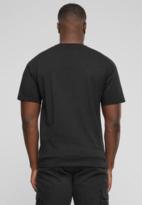 Czarny t-shirt z krótkim rękawem wykonany z bawełny. Prosty fason z okrągłym dekoltem. Gładka faktura, bez widocznych wzorów czy akcentów.