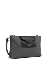 Borsa a tracolla sintetica grigia con patta in pelle nera, hardware argentato e chiusura con zip. Dotata di una tracolla removibile per maggiore versatilità.