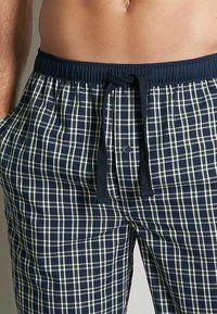 Pantalons de pyjama à carreaux navy avec une coupe décontractée, dotés d'une taille à cordon et de poches, fabriqués en tissu doux avec un motif en tartan.