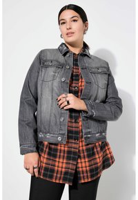 Harmaa farkkutakki hopeisilla yksityiskohdilla, kahdella etutaskulla ja haalistuneella pinnalla. Kerrostettu mustan ja oranssin ruudullisen paidan päälle.