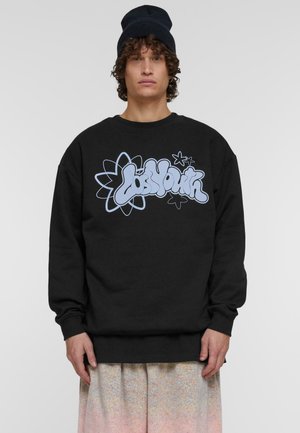 Sort sweatshirt med en afslappet pasform, der har et stort lysblåt graffiti-inspireret logo og blomstermotiv på forsiden. Lunt materiale, ribbet halsudskæring.