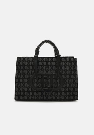 Sort og grå mønstret tote taske med flettede håndtag og stor oval logo-patch med sammenflettede bogstaver foran.