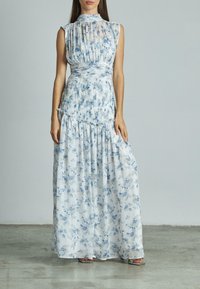 Maxikleid aus leichtem Stoff mit blauen Blumenmuster, plissiertem Oberteil, Taillendetails und fließendem Rock. Mit einem hohen Ausschnitt.