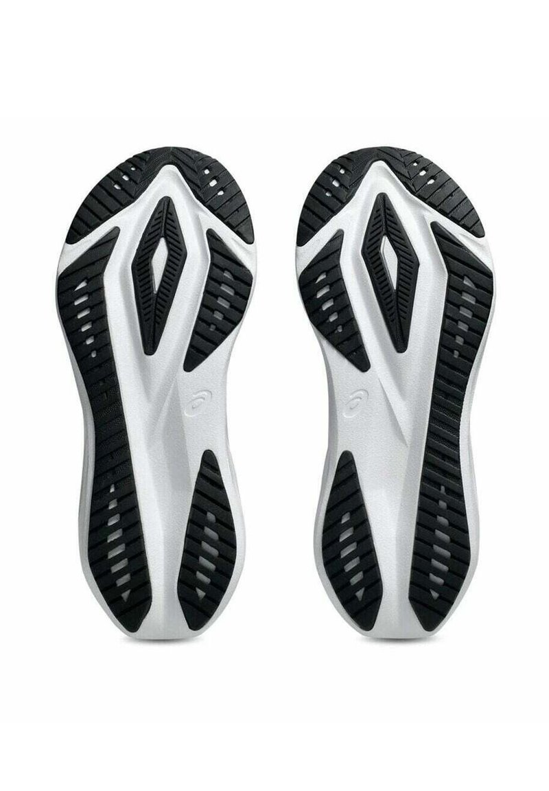 Semelles d'une paire de chaussures de sport noires et blanches montrant des motifs géométriques d'empreinte et des zones d'adhérence au bas.