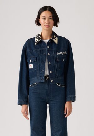 Giacca in denim con finitura blu scuro, colletto a motivo bovino, tasche frontali e ricami. Design cropped con dettagli in metallo argentato.