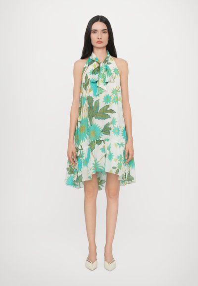 Abito senza maniche in bianco con stampa floreale verde e blu; tessuto leggero, design fluido, orlo asimmetrico, dettaglio fiocco coordinato.