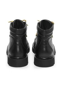 Un paio di stivaletti neri in pelle con colli imbottiti e suole in gomma spessa, visti da dietro.