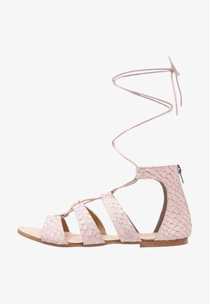 Lyserød sandal med en tekstureret, reptilagtig design, flere stropper og en lynlås bagpå. Inkluderer en snørebånd ved anklen for sikker fastgørelse.
