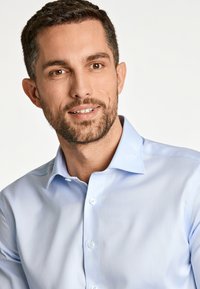 Lichtblauw button-up shirt met een nette kraag en lange mouwen. Gladde stof met een subtiele textuur en zichtbare knopen aan de voorkant.
