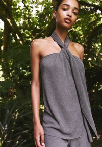 Gray, textured strapless top with a knotted design at the neckline and a flowing side drape, made from lightweight fabric.