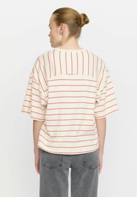 Striped short-sleeve top in cream with red horizontal stripes. Relaxed fit, round neckline, featuring a back patch pocket and soft fabric.