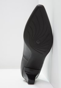 Czarny skórzany but na wysokim obcasie z zaostrzonym noskiem i zakrzywioną podeszwą, wyposażony w teksturowaną czarną gumową podeszwę oraz detal z logo.