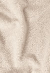 Tissu en polaire crème avec une surface douce et texturée, présentant une apparence légèrement froissée. Aucun motif ni accent distinct visible.