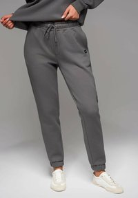 Graue Jogginghose aus weichem Material, mit einem elastischen Bund und Kordelzug, Bündchen an den Knöcheln und seitlichen Taschen.