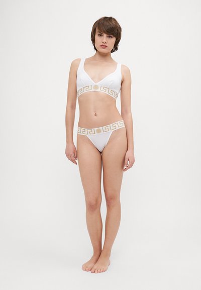 Bel beli bikini komplet z vrhnjim delom v obliki V in ustreznimi nizkimi hlačkami, okrašen z zlatim grškim ključem na pasu. Gladka tekstura.