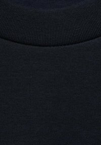 Mornarsko modra pletenina z rebrasto teksturo in okroglo ovratnikom. Material se zdi fleksibilen in mehak, z rahlimi odtenki.