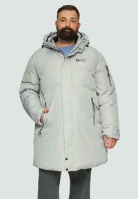 Lichtgrijze geïsoleerde parka met een capuchon, ritssluitingen en zwarte accenten op de ritsen; heeft een losse pasvorm en een gequiltde textuur.