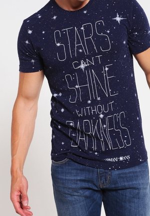 Granatowy t-shirt z gwiezdnym wzorem i napisem "GWIAZDY NIE MOGĄ ŚWIECIĆ BEZ CIEMNOŚCI" w białym pogrubionym druku. Materiał bawełniany.