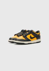 Schwarze und orange Nike-Sneaker mit perforierter Textur, Schnürdesign, gepolstertem Schaft und kontrastierender weißer Mittelsohle.