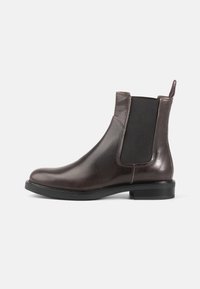 Brown leather Chelsea boots with elastic side panels, a rounded toe, and a low rubber heel. Smooth texture with minimal stitching details.