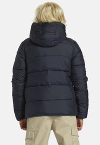 Námornícka puffer bunda s kapucňou, s prešívaným dizajnom a elastickými manžetami. Tkanina je hladká a vodoodolná.