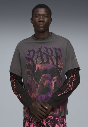 Grafisch oversized t-shirt in donkergrijs, met kleurrijke hondenprints en vetgedrukte letters. Lange zwarte mouwen met rode vlamaccenten.