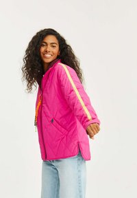 Jasně růžová prošívaná bunda se zipem vpředu, s žlutými bočními pruhy a detaily na stažení. Měkká textura a ležérní střih.