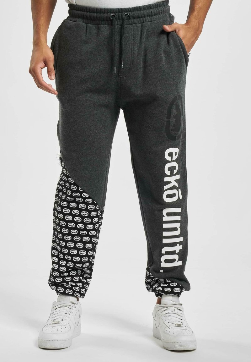 Grå sweatpants med en tapered fit, der har et sort mønstrede sidepanel, hvid tekst, elastisk talje og snøre.