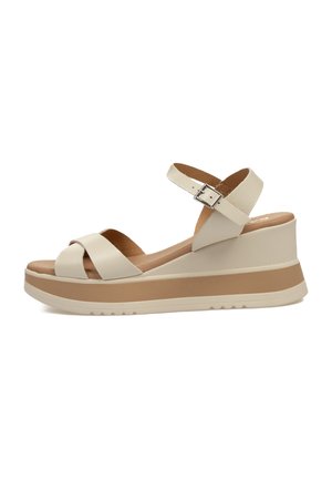 Sandalias de cuña beige con tiras entrecruzadas, correa de tobillo ajustable, plantilla acolchada y una plataforma texturizada con una banda de acento marrón.