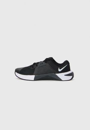 Black and white Nike low-top athletic shoe with mesh upper, lace closure, and Nike swoosh on the heel against plain background.