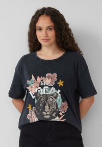 Zwarte oversized T-shirt met een tijgerafbeelding, kleurrijke bloem- en steraccenten, en een ronde hals. Zacht katoenmateriaal met korte mouwen.