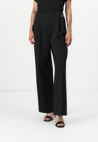 Black wide-leg trousers made of smooth fabric, featuring a flat front, side pockets, and a subtle silver accent on the waistband.