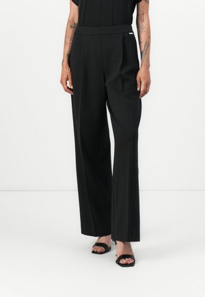 Black wide-leg trousers made of smooth fabric, featuring a flat front, side pockets, and a subtle silver accent on the waistband.