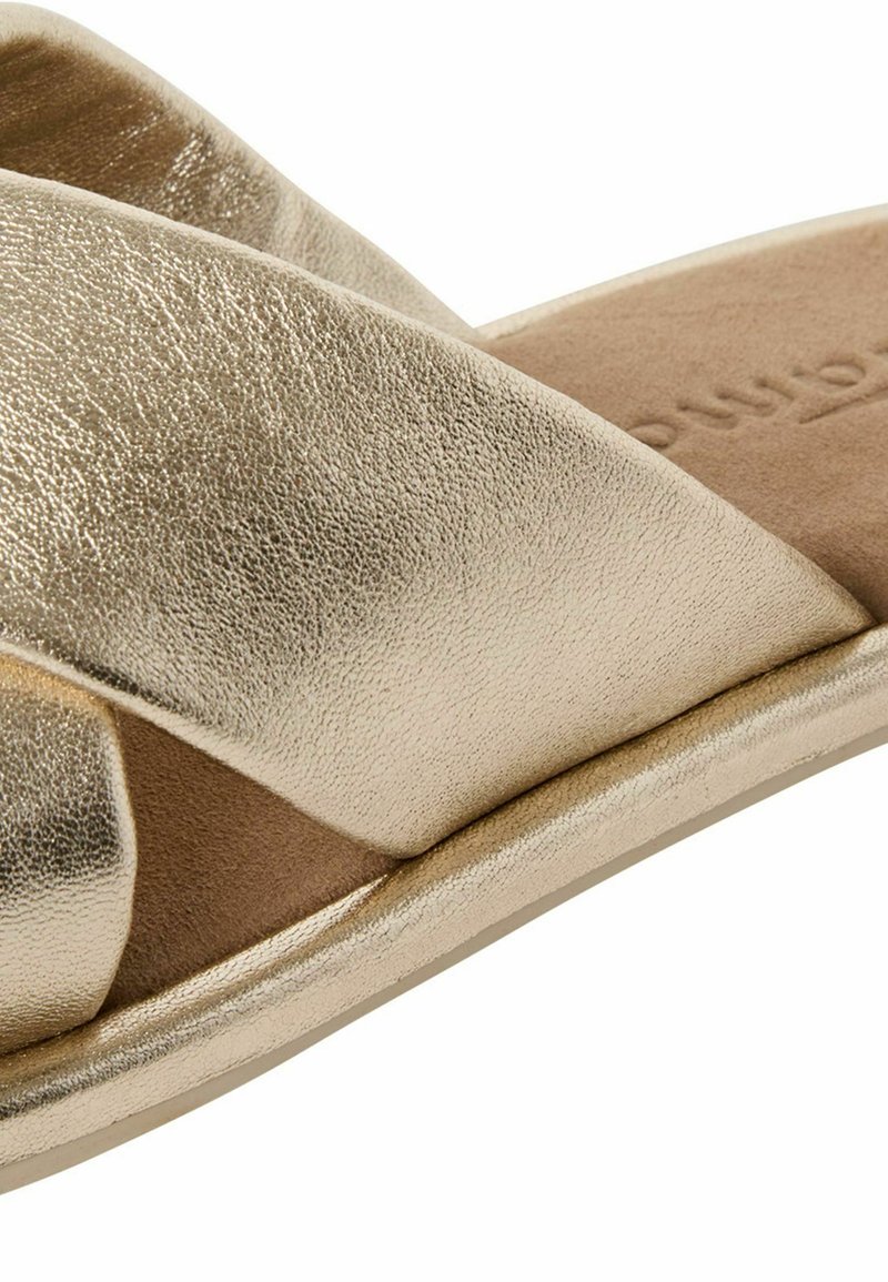 Gouden metallic slide sandalen met kruisende banden, een gladde textuur, een zachte bruine voetbed en een minimalistisch ontwerp. Platte zool voor casual gebruik.