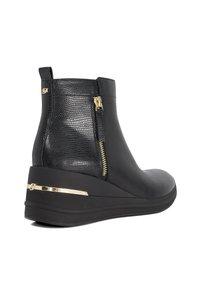 Zwarte enkellaars met een textured leren paneel. Kenmerkt zich door een wiggenhak, gouden ritsdetail en een metallic accent op de hak. Glad afgewerkt.