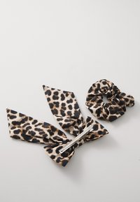 Set pribora za kosu s uzorkom leoparda, uključujući ravnu mašnu s kopčom i odgovarajući gumicu za kosu, izrađeni od glatkog materijala u bež i crnim tonovima.